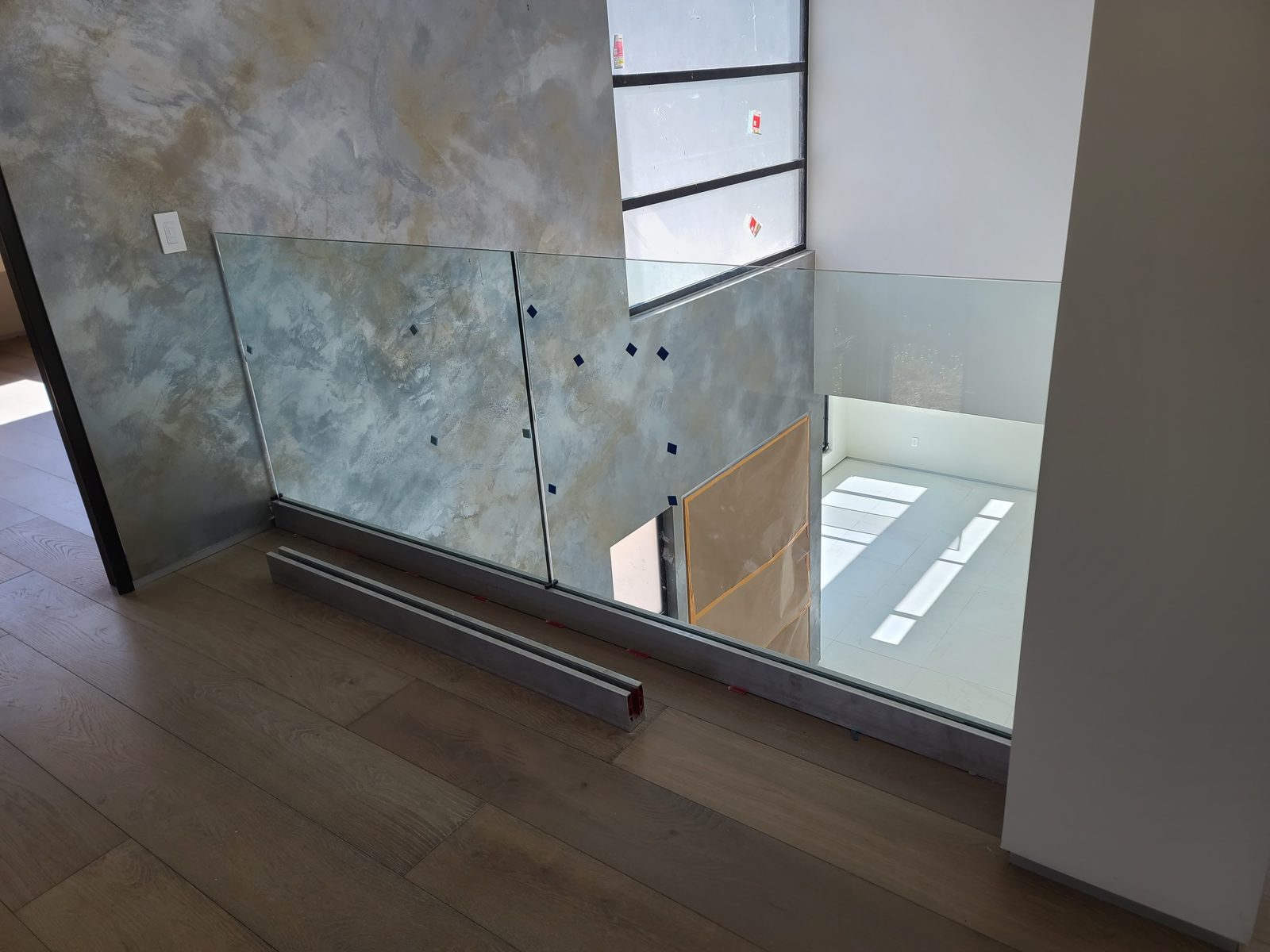 Frameless glass stair railing on a hardwood landing by Mad Touch Glass