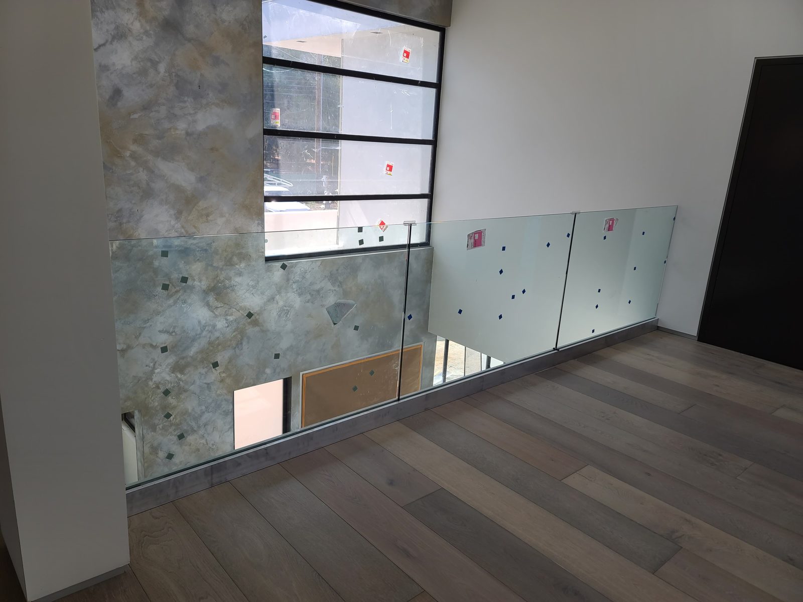 Frameless glass landing railing beside a stone feature wall by Mad Touch Glass
