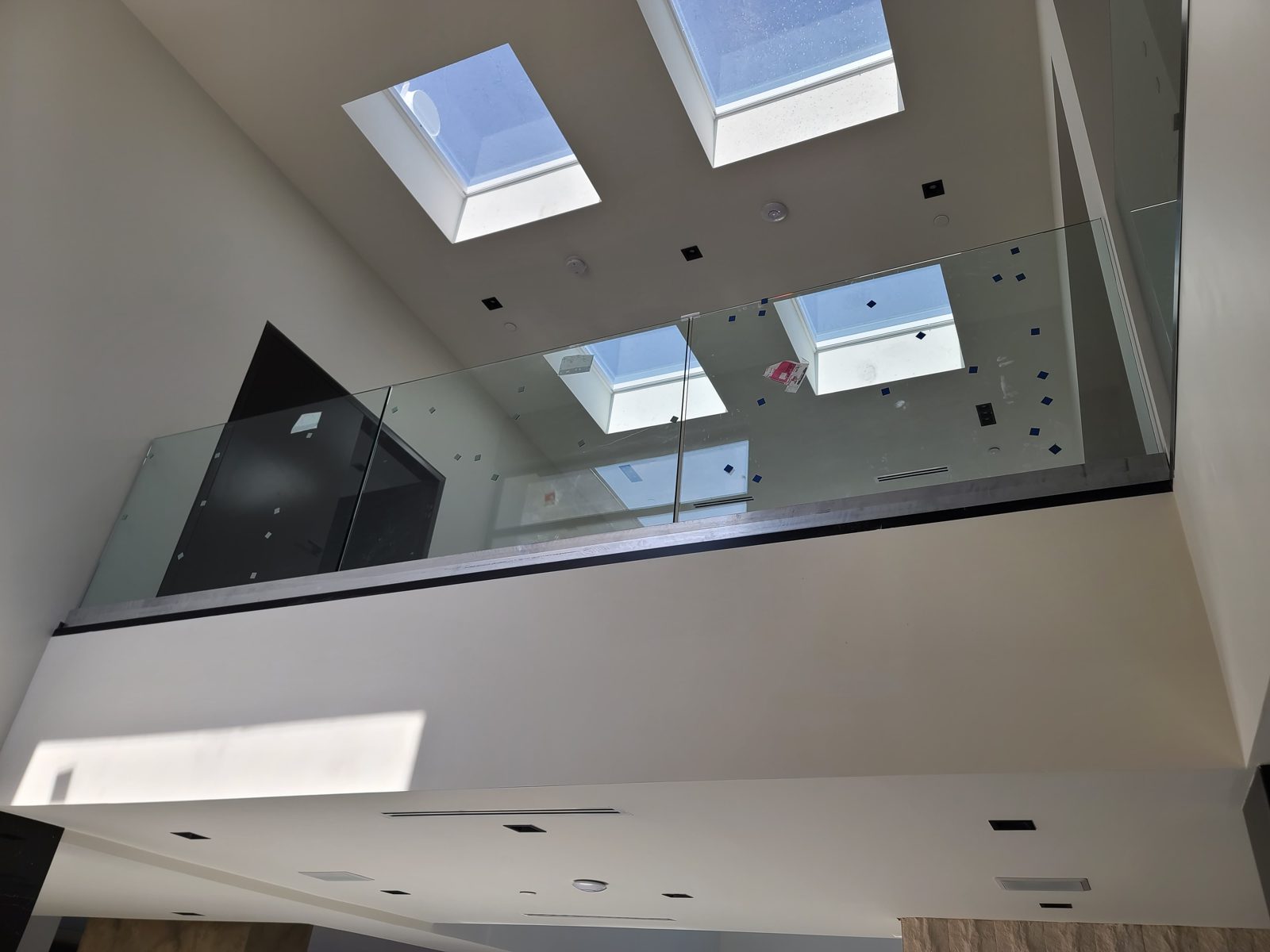 Frameless glass railing on an upper level under skylights by Mad Touch Glass