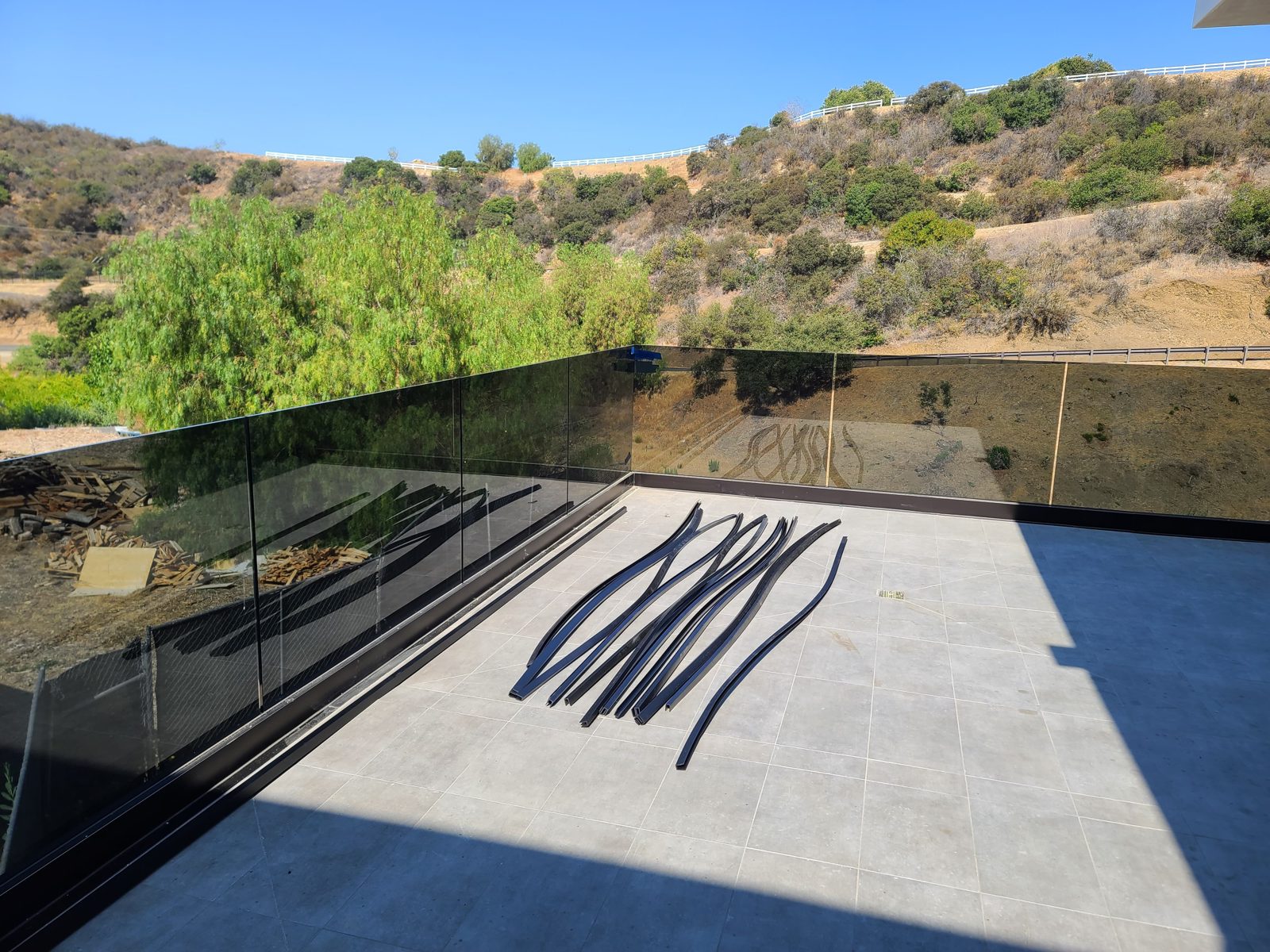 Black-tinted frameless glass patio railing with a mountain view by Mad Touch Glass